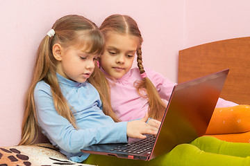 Image showing Two girls pushing a search query on a laptop keyboard