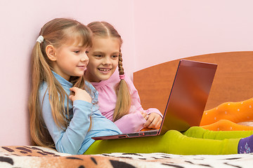 Image showing Two girls watching something funny in notebook