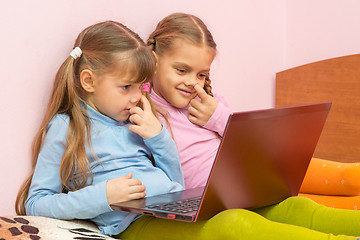 Image showing Two girls picking his nose and looking at a laptop screen