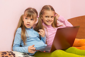 Image showing Two girls were distracted from the laptop and looked toward