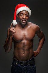 Image showing Muscular black shirtless young man in Santa Claus hat