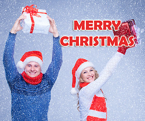 Image showing The woman and man dressed in santa hat holding with a Christmas gifts