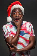 Image showing Muscular black surprised young man in Santa Claus hat