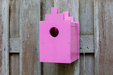 Image showing Pink birdhouse on a wooden fence