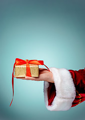 Image showing Hand of Santa Claus holding a gift on blue background