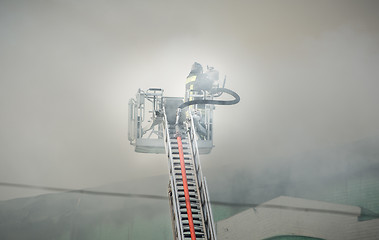 Image showing Firefighters in action fighting, extinguishing fire, in smoke.