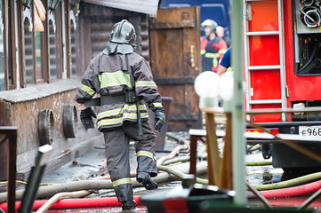 Image showing fire fighters walking away building in the drops of water after putting out the