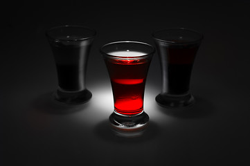 Image showing red and tow shot glass on a dark background in the spot light