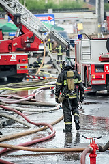 Image showing fire fighters walking away building in the drops of water after putting out the