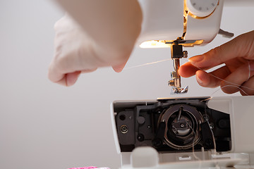 Image showing Girl inserts thread in sewing-machine