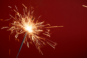 Image showing Flaming sparkler on red background