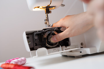 Image showing Woman inserts bobbin in sewing-machine