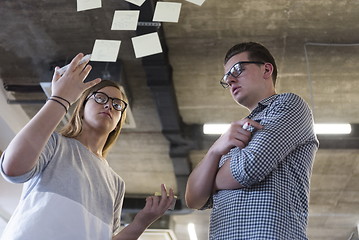 Image showing young couple at modern office interior writing notes on stickers