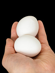 Image showing Closeup of a male hand, with a pair of white chicken eggs, isola