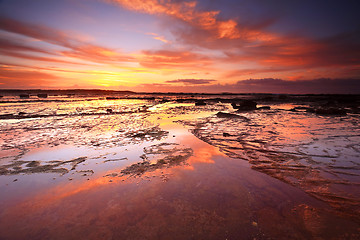 Image showing Sunrise skies reflecting on the exposed rocks in low tide