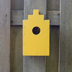 Image showing Yellow birdhouse on a wooden fence