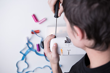 Image showing Man with screwdriver repairing sewin-machine