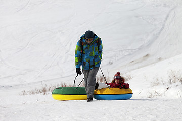 Image showing Father and daughter with snow tube in sun winter day