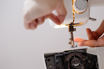 Image showing Seamstress inserts thread in sewing-machine