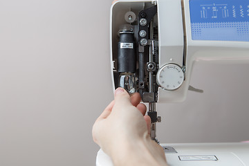 Image showing Young man mending sewing machine