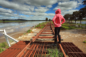 Image showing Floodwaters run under buckled train tracks