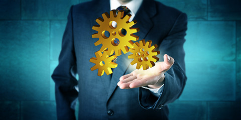 Image showing Business Man Offering A Golden 3D Gear Drive