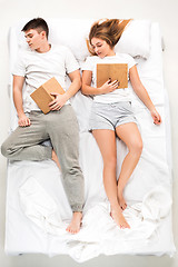 Image showing The young lovely couple lying in a bed with books