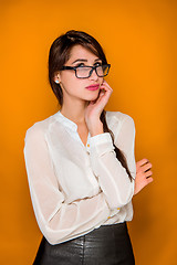 Image showing The serious frustrated young beautiful business woman on orange background