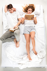 Image showing The young lovely couple lying in a bed with books