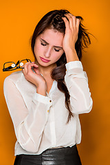 Image showing The serious frustrated young beautiful business woman on orange background