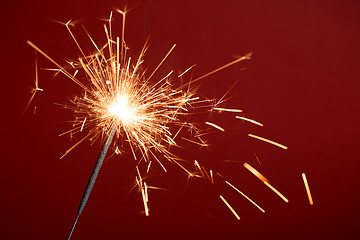 Image showing Burning sparkler on red background