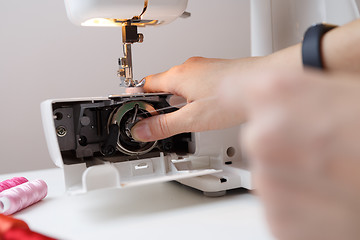 Image showing Girl inserts bobbin in sewing-machine