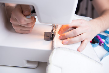 Image showing Young girl stitching white cloth