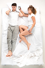 Image showing The young lovely couple lying in a bed with alarm clock