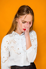 Image showing The serious frustrated young beautiful business woman on orange background