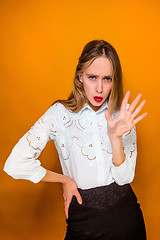 Image showing The serious frustrated young beautiful business woman on orange background