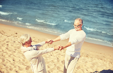 Image showing happy senior couple holding hands on summer beach