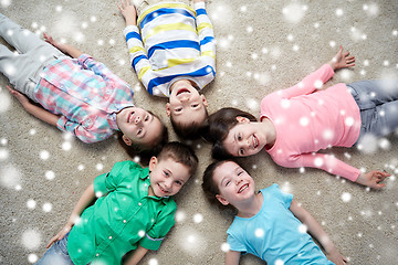 Image showing happy smiling children lying on floor over snow