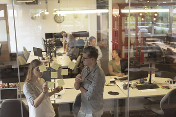 Image showing young couple at modern office interior writing notes on stickers