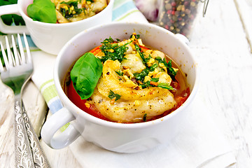 Image showing Fish baked with tomato and basil in white bowl on board