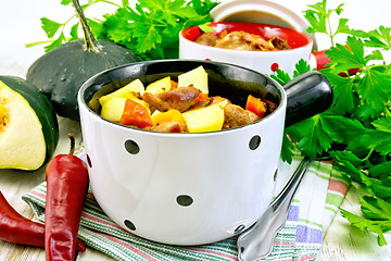Image showing Roast meat and vegetables in white pots on light board