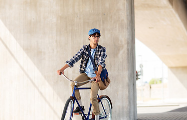 Image showing young hipster man with bag riding fixed gear bike