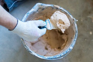 Image showing Builder's hand with spatula and cement