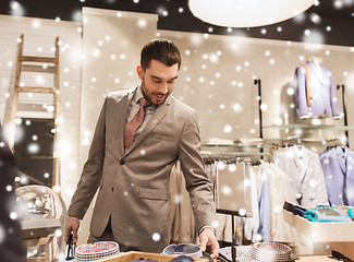 Image showing happy young man choosing shirt in clothing store