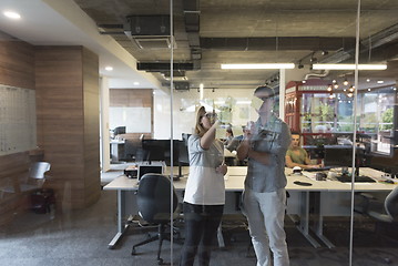 Image showing young couple at modern office interior writing notes on stickers