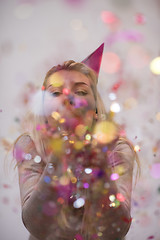 Image showing woman blowing confetti in the air