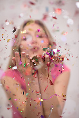 Image showing woman blowing confetti in the air