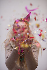 Image showing woman blowing confetti in the air