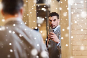 Image showing man in suit taking mirror selfie at clothing store