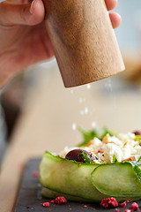 Image showing close up of hand with salt shaker salting salad